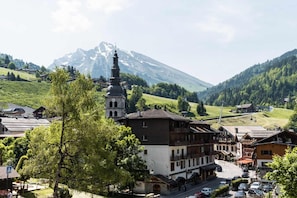 A mountain town with a prominent church tower, traditional buildings, and a view of a snow-capped mountain.