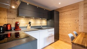 A modern kitchen with a central island, white cabinetry, and wooden accents.