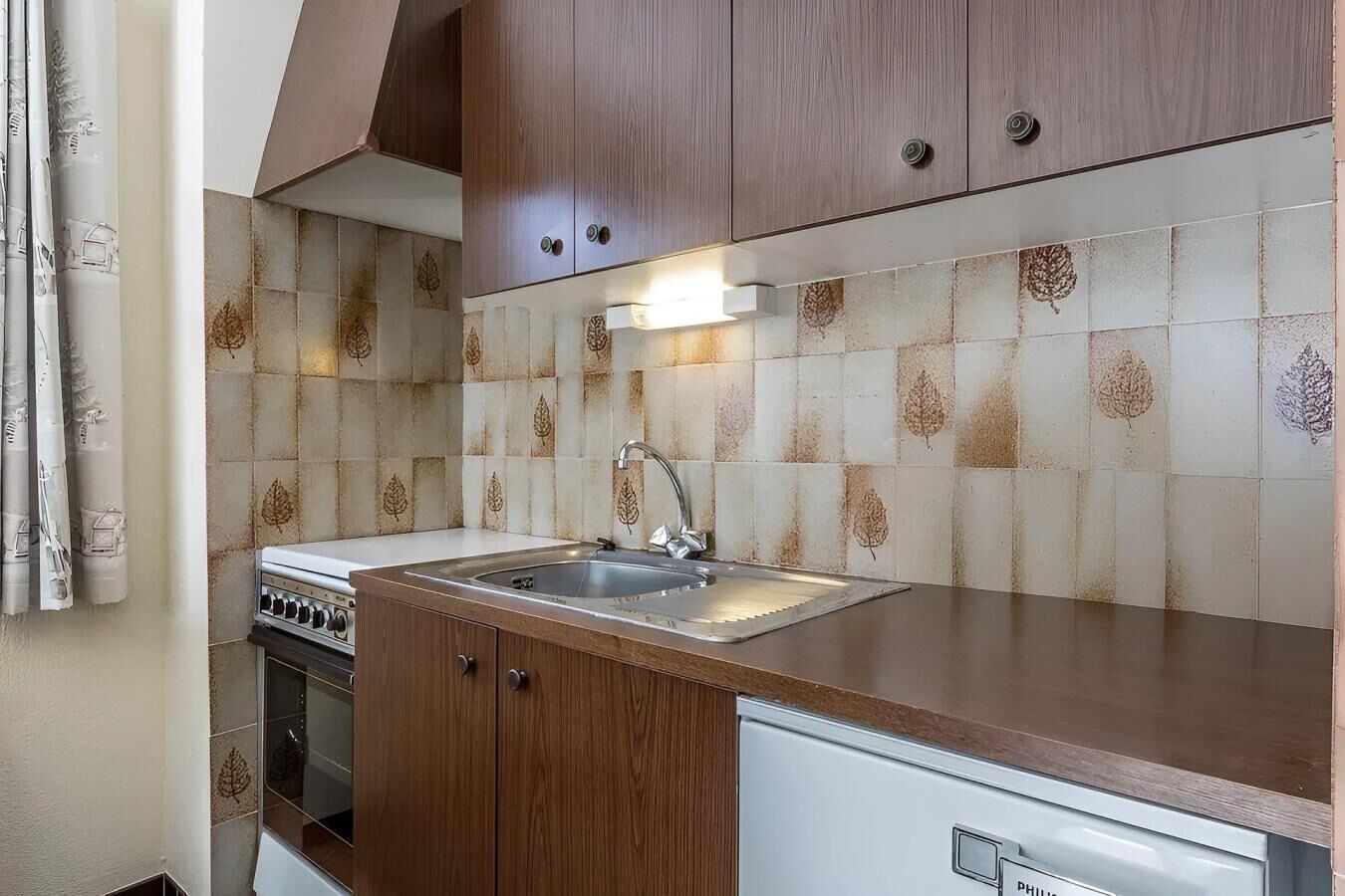 A compact kitchen with a sink, stove, and dishwasher.