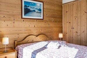 Ein Zimmer mit Holzwänden, einem Bett, zwei Nachttischlampen und einem gerahmten Bild an der Wand.
