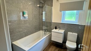 Un baño moderno con bañera, ducha, inodoro y tocador.