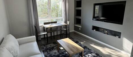 A modern living room with a sofa, coffee table, and a flat-screen TV mounted on the wall.