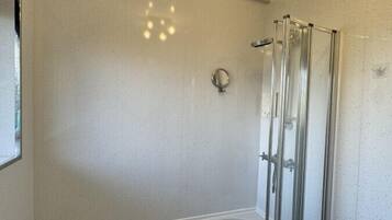 Et badeværelse med badekar, brusekabine i glas og håndvask.