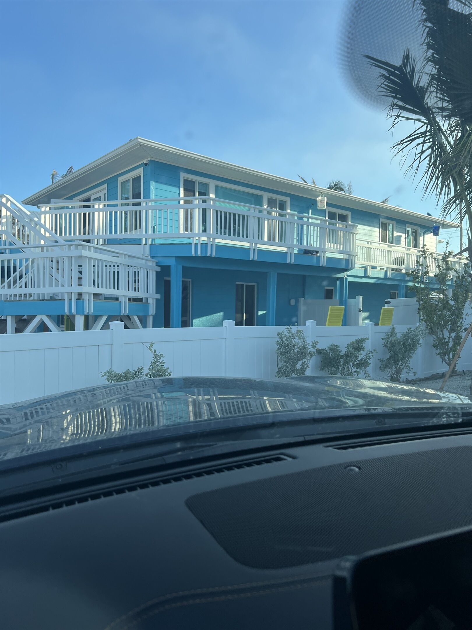 A two-story building with a balcony, white railings, and a white fence.