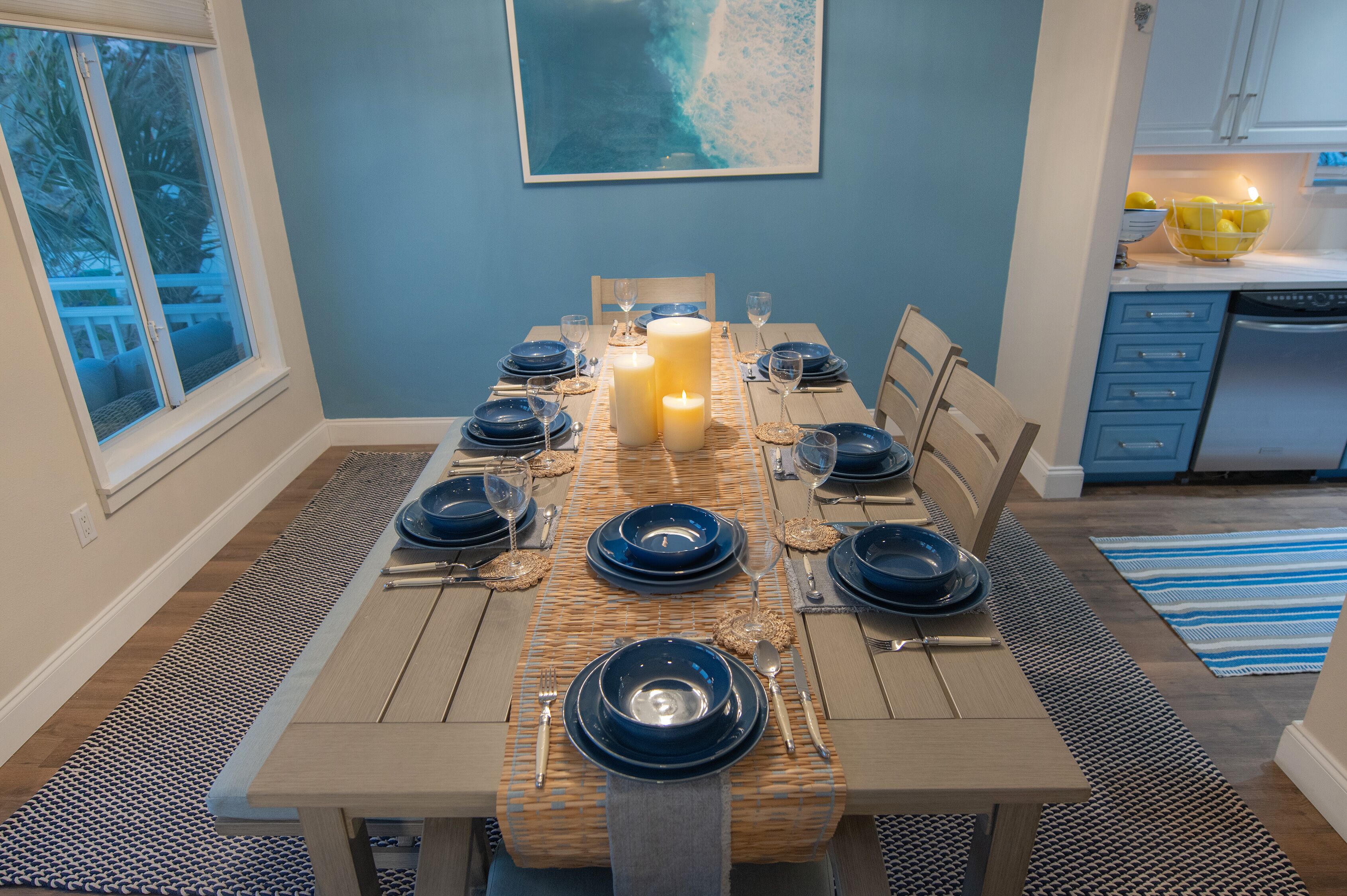 Comedor con una mesa dispuesta para seis personas, con platos azules y una vela en el centro.
