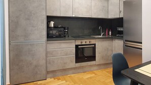 A modern kitchen with grey cabinets, a built-in oven, a coffee maker, and a refrigerator. - Apart in the Heart Of Athens (Athina)