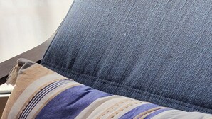 A close-up of a textured blue fabric, likely a couch or chair cushion, with a striped pillow partially visible. - Apart in the Heart Of Athens (Athina)