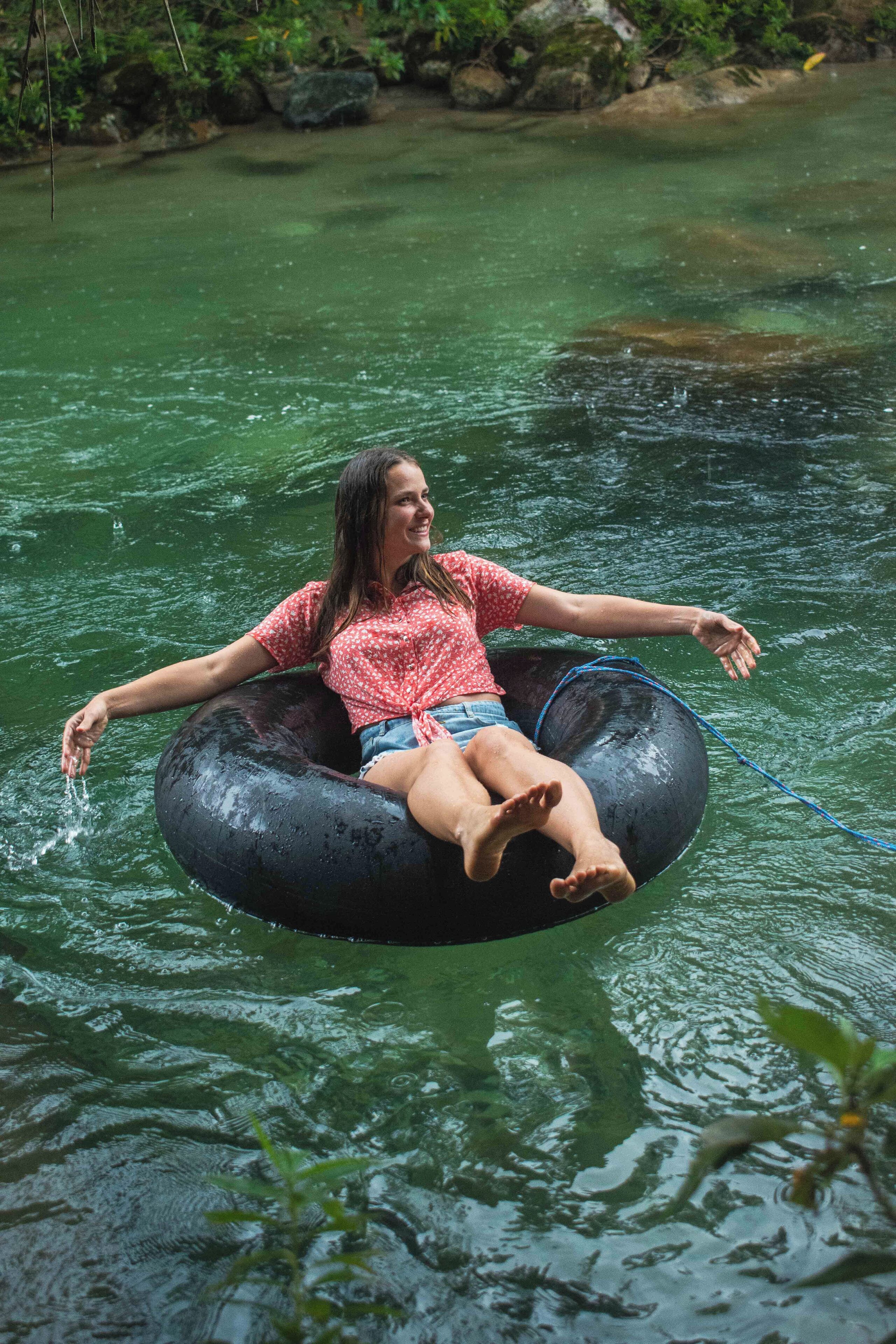 A person floating on a black inflatable tube in a body of water.