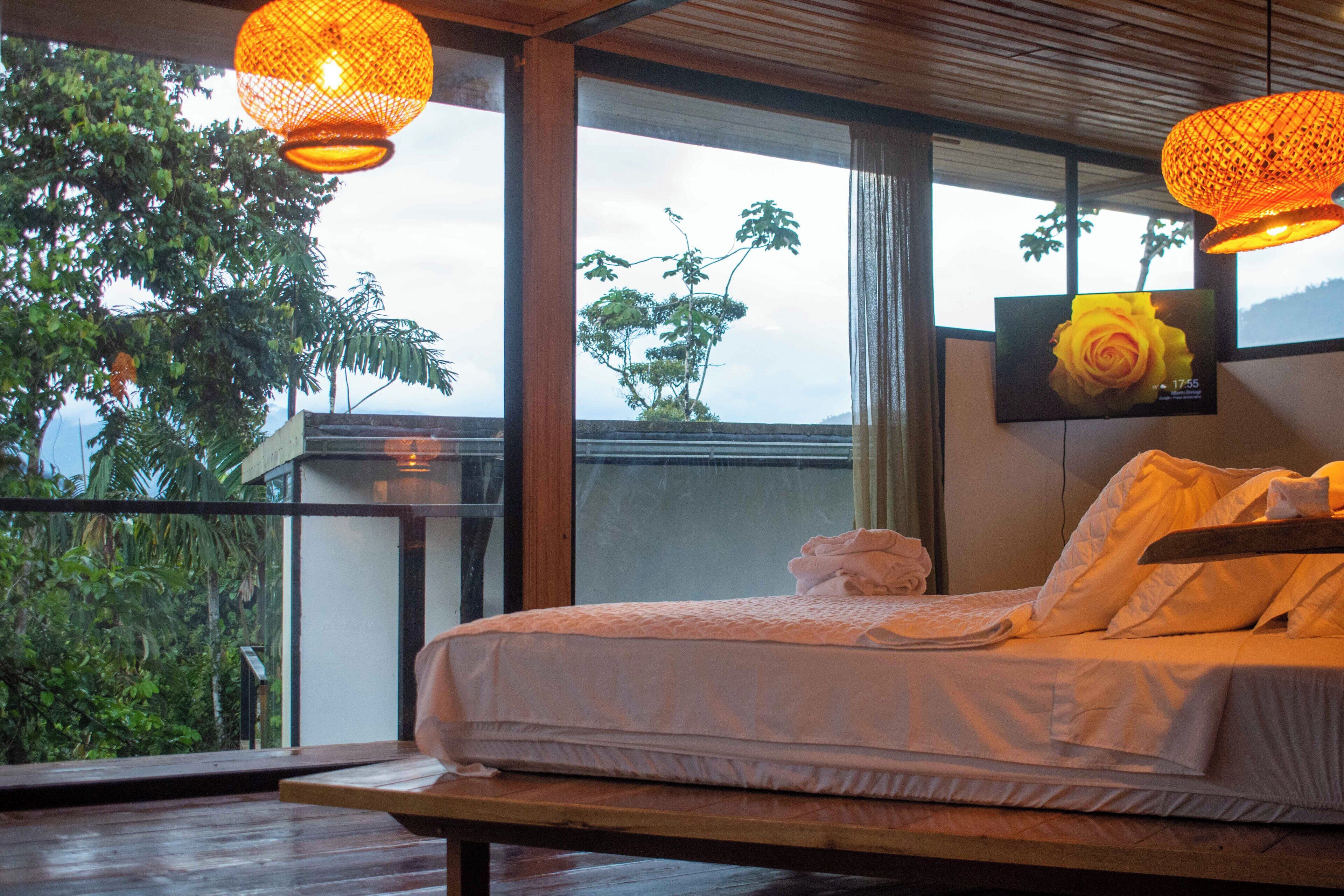 Une chambre avec une grande fenêtre, un lit et une table en bois.