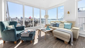 A spacious living room with a large window, a sofa, a chair, and a coffee table.