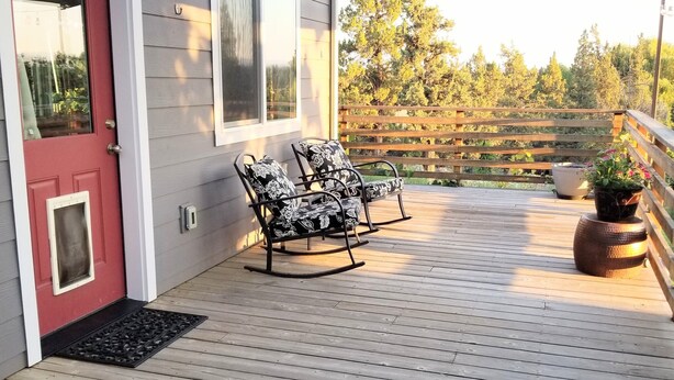 Eine Holzterrasse mit einem Schaukelstuhl und einem Blumentopf.