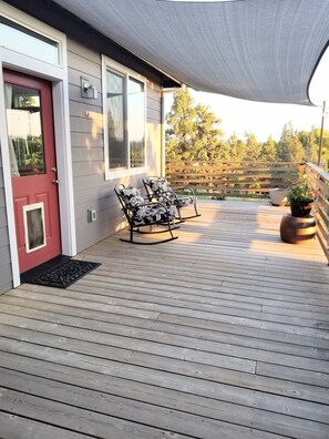 A wooden deck with a rocking chair and a potted plant.