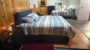 Une chambre avec deux lits, des murs en bois, une commode et une table de chevet.