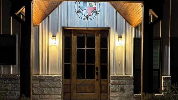 A building entrance with a wooden door, stone walls, and a metal roof. -  Forget your worries in this spacious and serene space. (Copperas Cove)