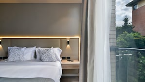 Ein modernes Hotelzimmer mit einem großen Bett, Nachttischen und Blick ins Freie.