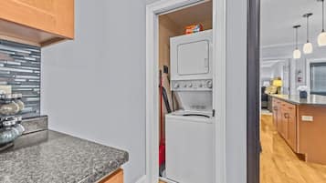 A compact kitchen with a built-in oven and a small refrigerator, a granite countertop, and wooden cabinets.