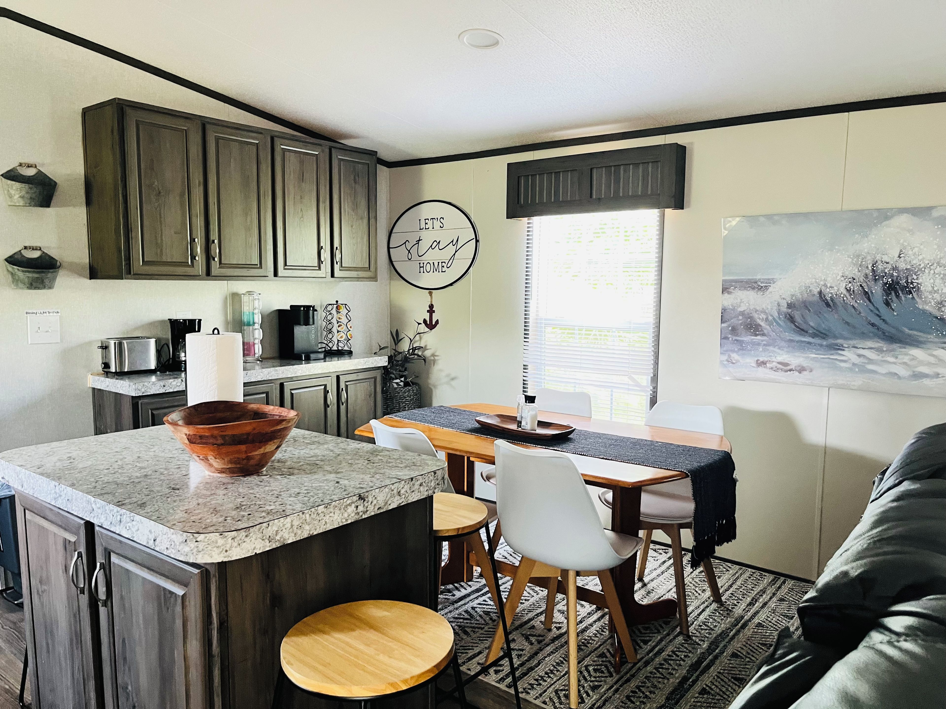 A modern kitchen with granite countertops, wooden cabinets, and a dining area with a table and chairs.