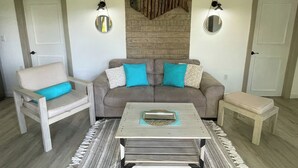 A living room with a grey sofa, a white armchair, a coffee table, and two wall-mounted lamps.