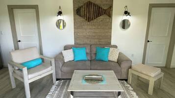 A living room with a grey sofa, a white armchair, a coffee table, and two wall-mounted lamps.