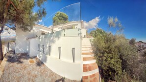 Una casa moderna con fachada blanca, techo curvo y un pequeño porche.