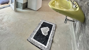 Een keuken met een witte koelkast, een geel spoelgedeelte en een zwart-wit tapijt.
