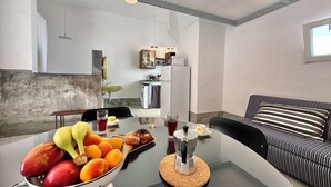 Een moderne keuken met een eetgedeelte, een koffiezetapparaat en een fruitschaal op tafel.