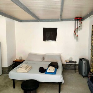 A single-bed room with a simple layout, including a bed, bedside tables, a desk, and a suitcase. - Lu Parmientu - One Bedroom Apartment, Sleeps 2 (Parabita)