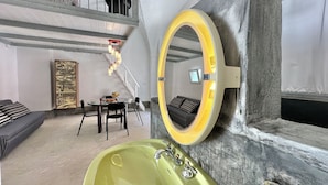 Een modern interieur met een ronde spiegel, een groene wastafel, een eethoek en een trap.