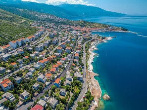An aerial view of a coastal town with residential buildings, a marina, and a clear blue sea. - Dalibor by Interhome (Senj)