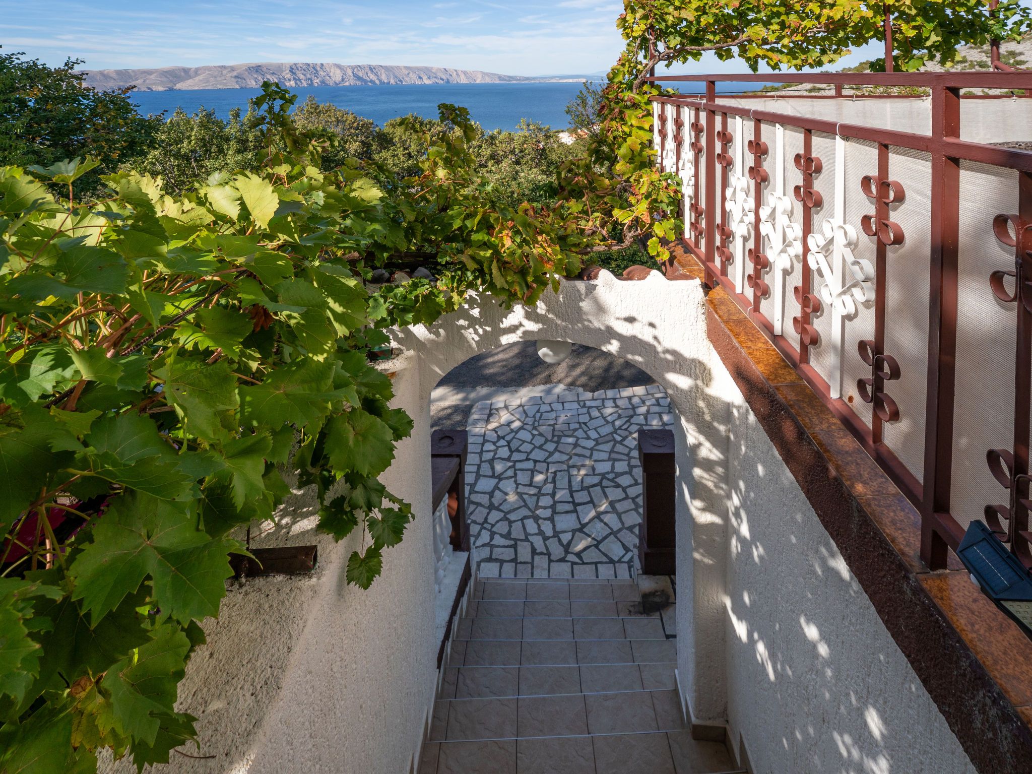 Un escalier en pierre mène à une terrasse d’où l’on peut admirer la mer et les montagnes.