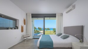 A modern bedroom with a large bed, a view of the sea, and a balcony. - Stunning beachfront retreat, private tennis court & infinity pool (Rhodes)