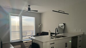 Een moderne keuken met een groot eiland, een inbouw vaatwasser en een schuifdeur naar een balkon.