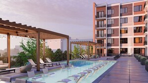 Een dakzwembad met ligbedden en een pergola, omringd door een modern appartementencomplex.
