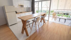 Una cocina moderna con armarios blancos, una mesa de madera y taburetes de bar.