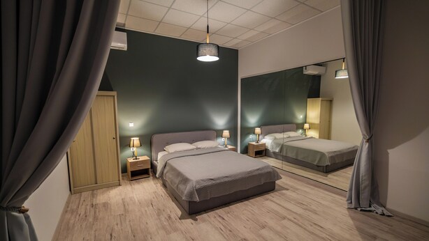 Un dormitorio con una cama grande, mesitas de noche, un espejo y una lámpara en el techo.