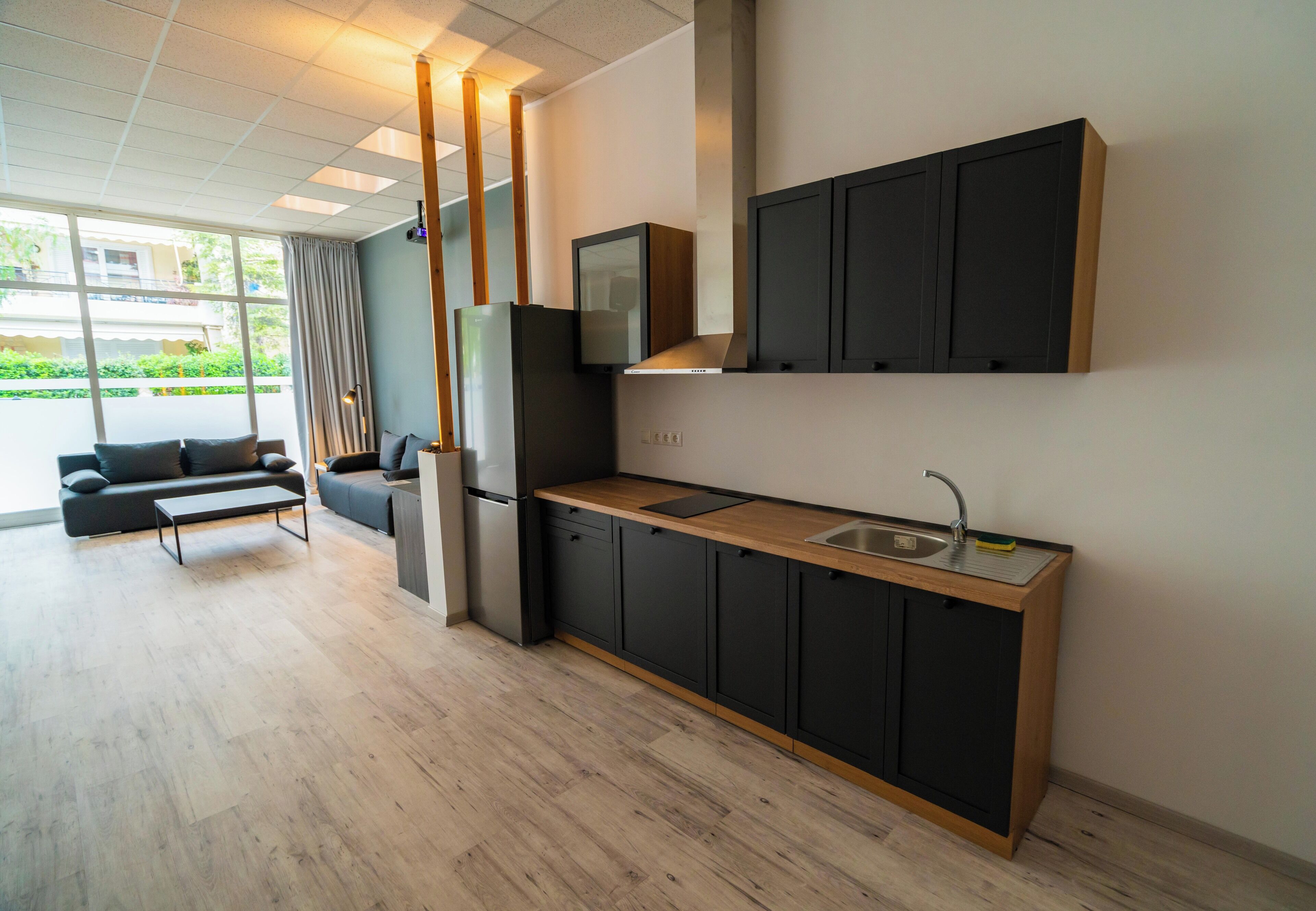 A modern kitchen with black cabinets, a wooden countertop, and a built-in oven.