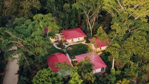 An aerial view of a property with multiple buildings surrounded by dense forest.