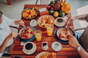 A breakfast setting with plates of food, fruit, and beverages on a wooden table.