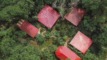 Vista aérea de una propiedad con cuatro edificios de techo rojo rodeados de abundante vegetación.