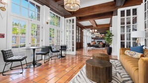 A spacious lobby with large windows, a wooden floor, and a mix of seating areas including a sofa and chairs. - Santa Rosa Stonehouse Private Wine Country Retreat (Santa Rosa)