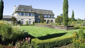A large, two-story building with a symmetrical facade, multiple windows, and a well-maintained lawn. - Santa Rosa Stonehouse Private Wine Country Retreat (Santa Rosa)