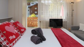 Une chambre d’hôtel avec un lit, une télévision, un canapé et une vue sur un bâtiment à l’extérieur.