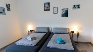 A double bed with striped bedding and two bedside tables with lamps. - Guest at Gastel's FeWo 3-6 persons gladly workers or fitters (Fischach)