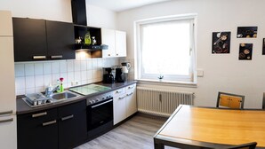 A modern kitchen with black and white cabinetry, a built-in oven, and a window providing natural light. - Guest at Gastel's FeWo 3-6 persons gladly workers or fitters (Fischach)