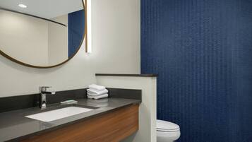 Un baño moderno con tocador de madera oscura, un lavabo blanco y un inodoro.