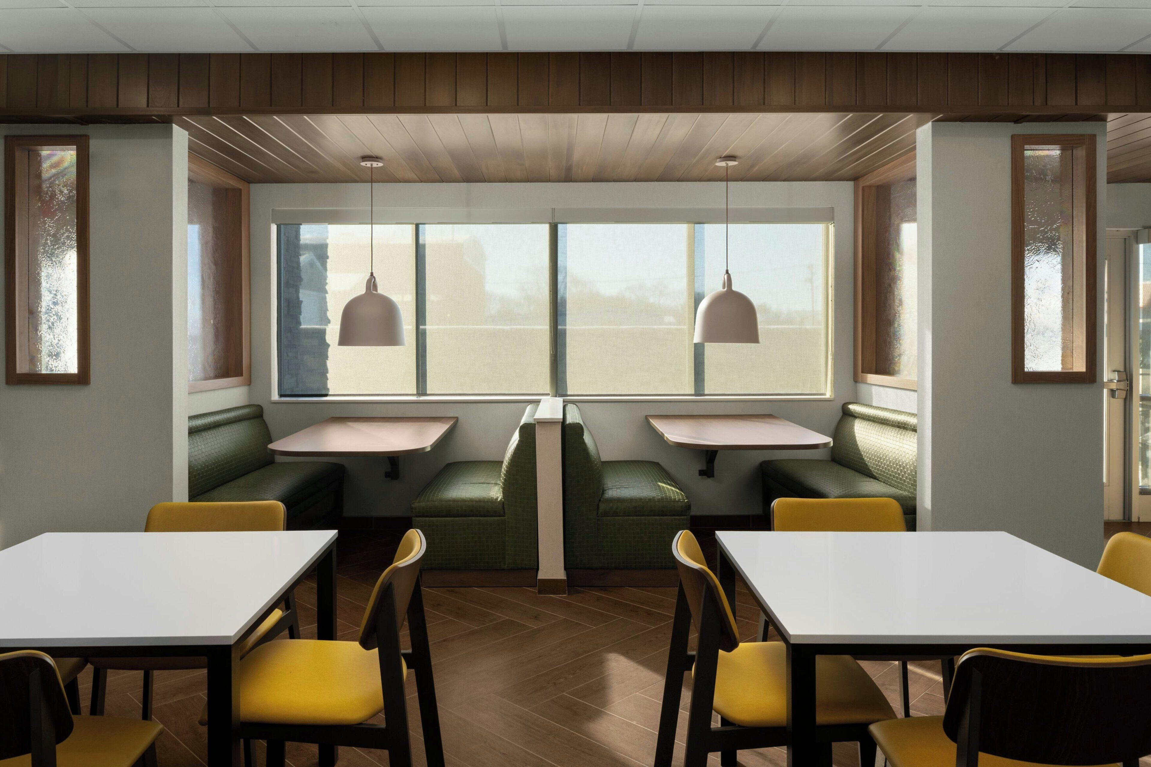 Un restaurante con mesasychairs, techo de madera y lámparas colgantes.