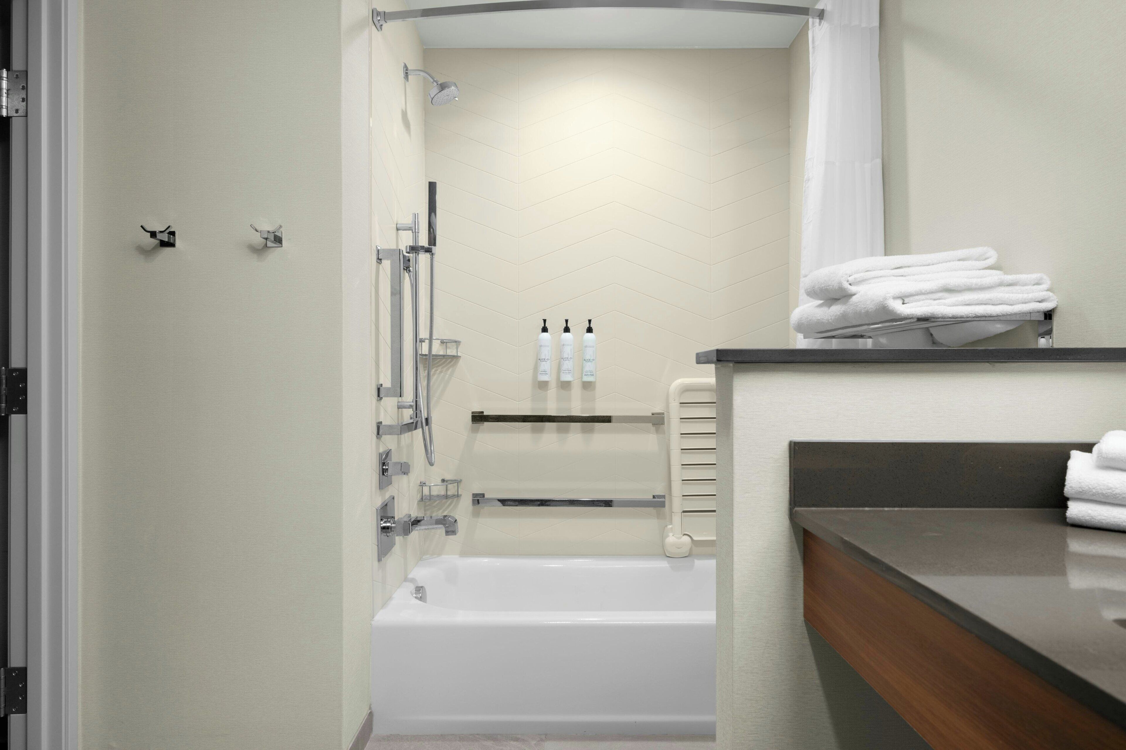 Un baño moderno con bañera, ducha y tocador con un perchero.