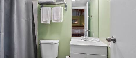 A bathroom with a toilet, sink, and shower curtain.