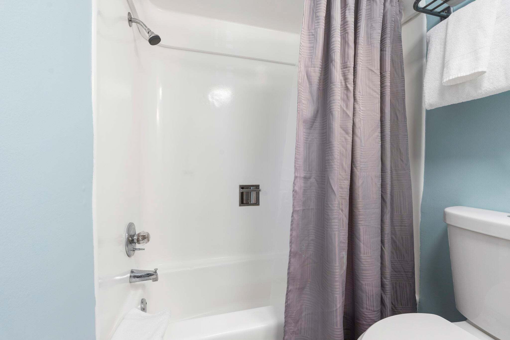 Un baño con ducha, inodoro y toallero.