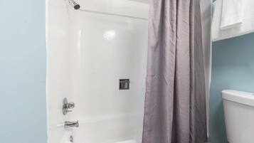 Un baño con ducha, inodoro y toallero.